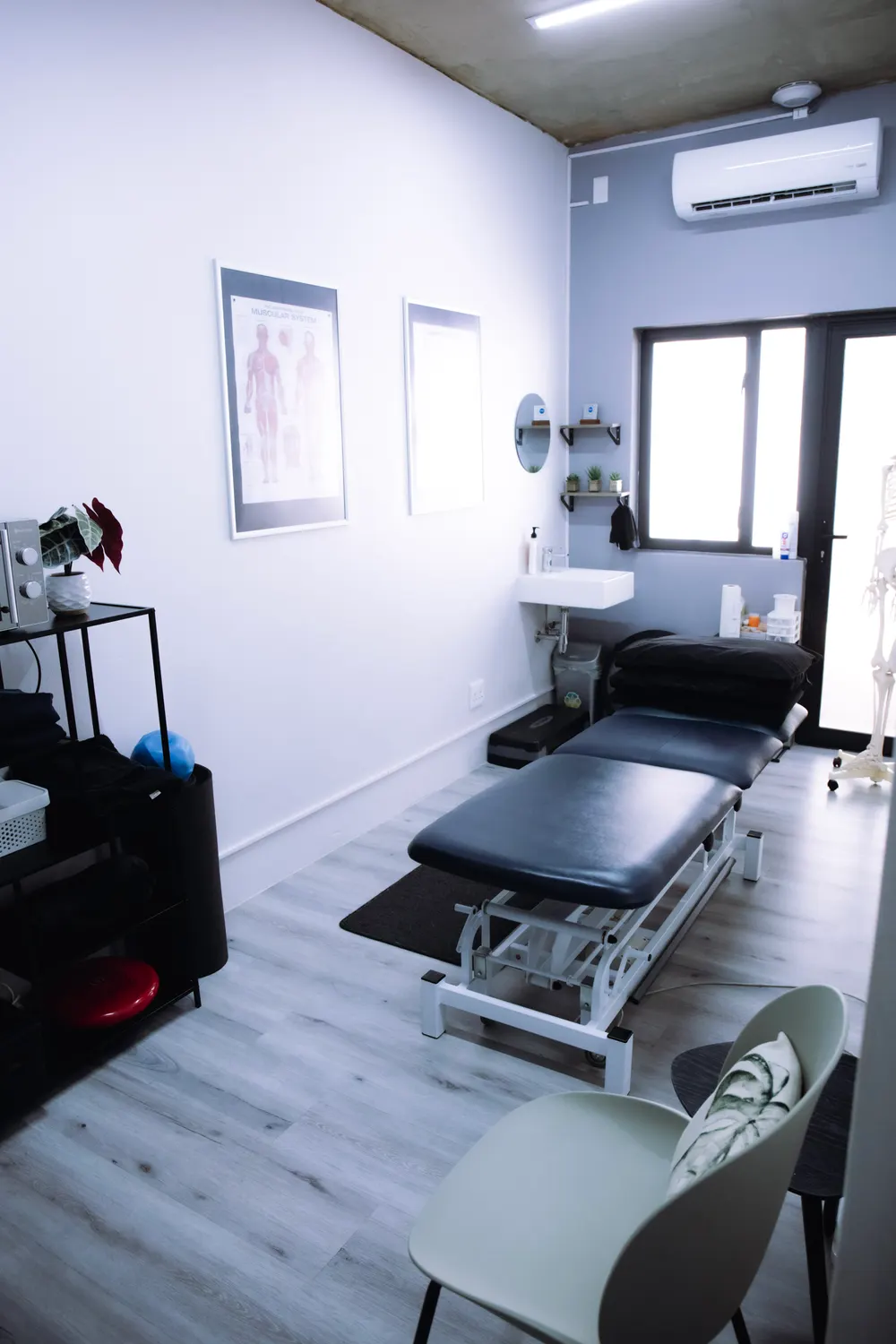 Treatment room at the Ashlea Gardens practice, with treatment couch, anatomy charts and a wash basin