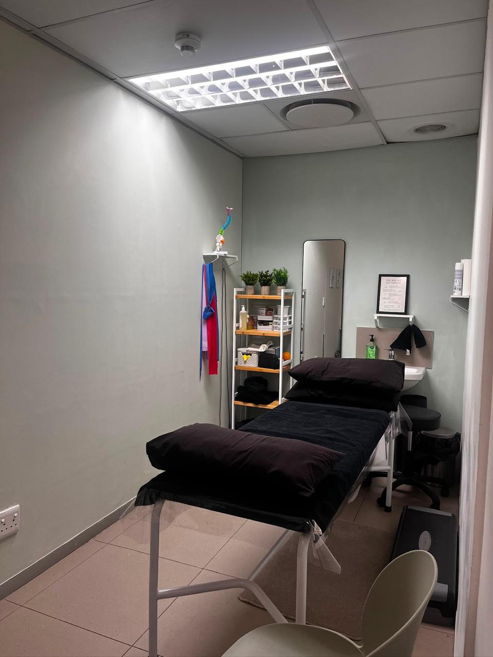Treatment room at the Midstream practice, with treatment couch, supply shelving and a wash basin